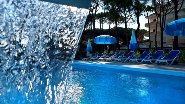 A pool area with lounge chairs and umbrellas. - Aparthotel la Pineta (Jesolo)