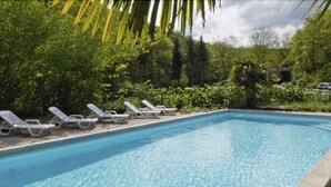 A rectangular swimming pool with clear blue water, surrounded by lounge chairs and greenery. - Hôtel La Cascade (Saint-Genis-les-Ollieres)