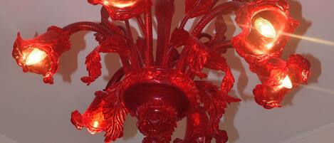 A chandelier with multiple red glass shades and a white ceiling medallion.
