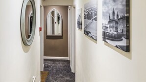 A hallway with a mirror, a door with a window, and three black-and-white photographs on the wall. - Burlington Hotel Hull City Centre (Hull)