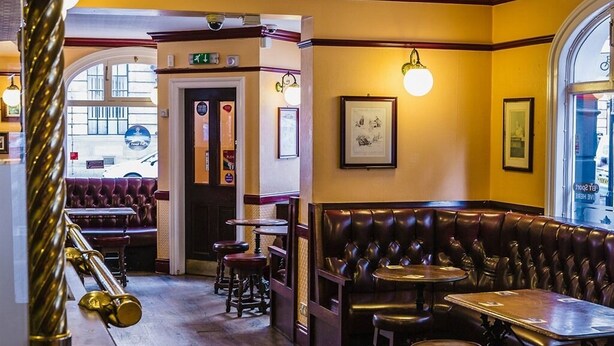 A restaurant interior with leather booths, wooden tables, and framed artwork on the walls. - Burlington Hotel Hull City Centre (Hull)