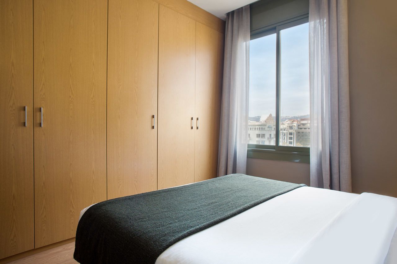 Et hotelværelse med en stor seng, et træskab og et vindue med udsigt over byen.
