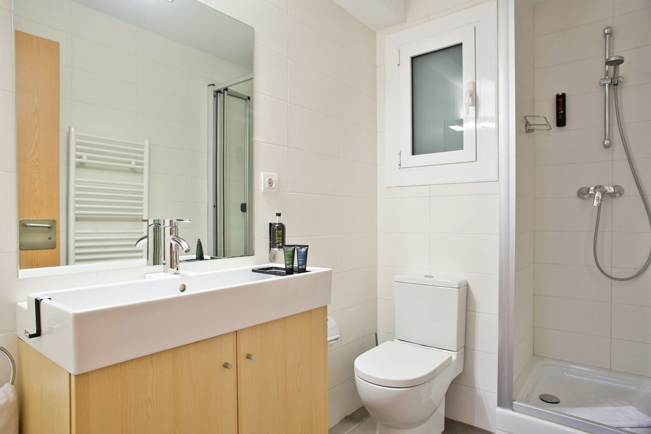 A modern bathroom with a white sink, mirror, and toilet.