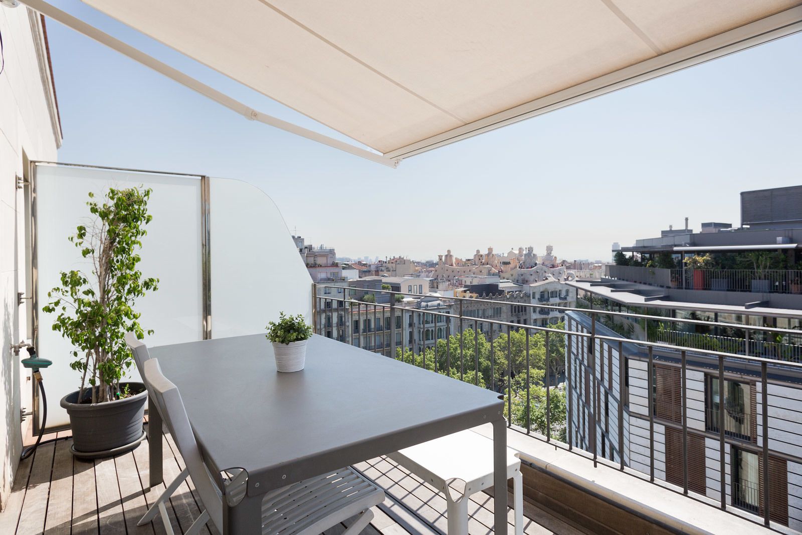 Un balcón con una mesa y plantas en macetas, con vistas a la ciudad.
