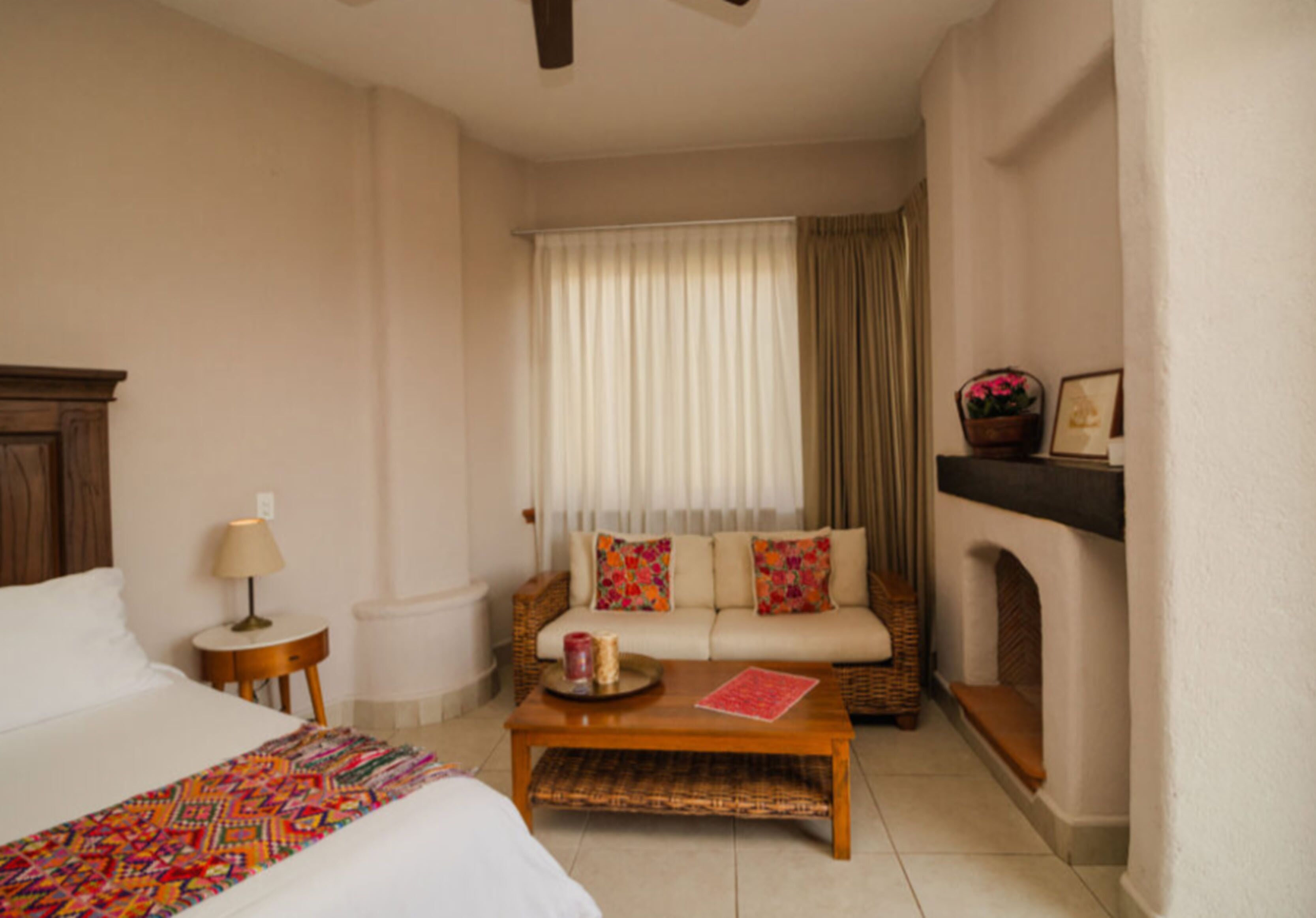 Une chambre d’hôtel avec un lit, un canapé, une table basse, une lampe et une cheminée.
