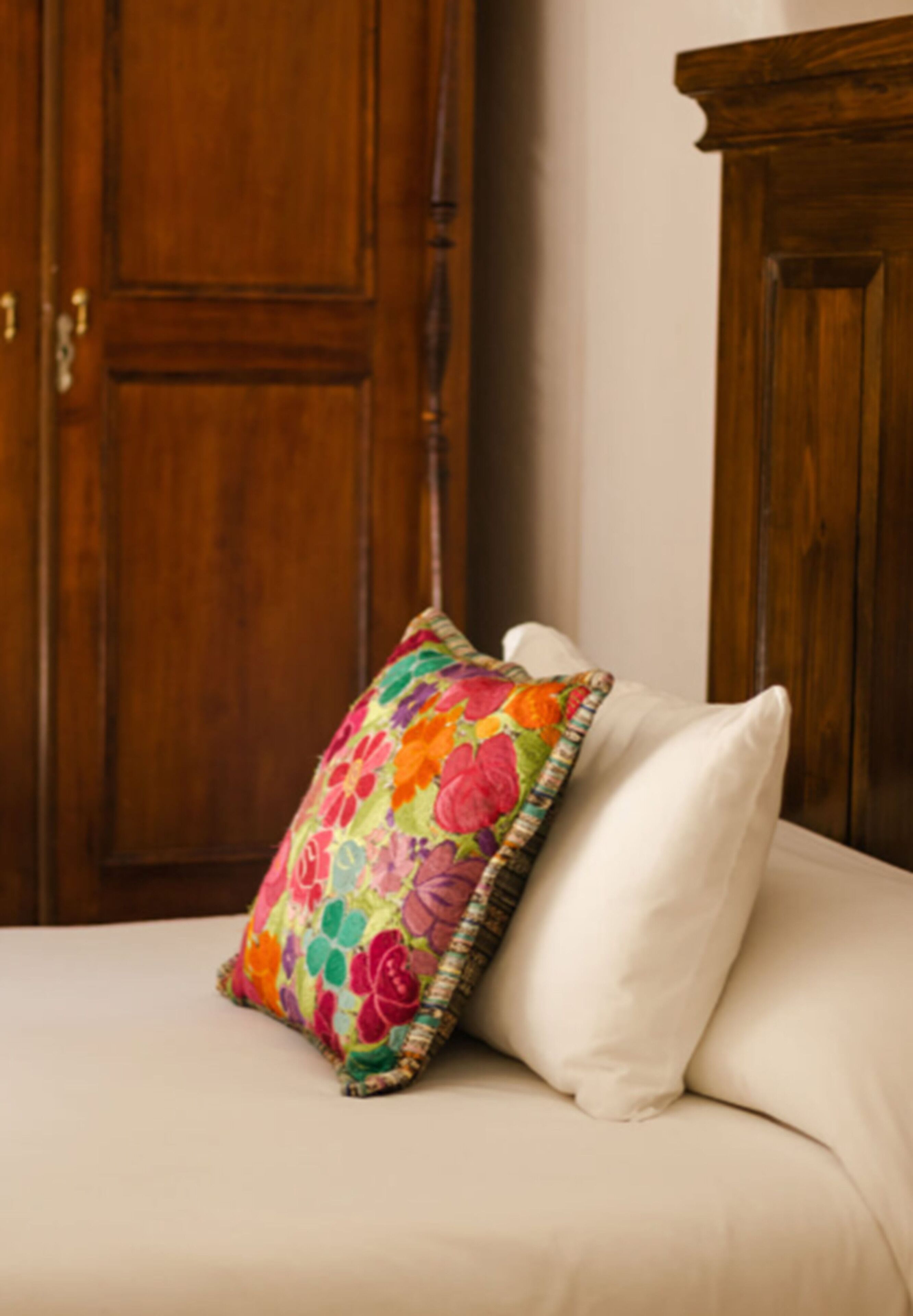 Una cama con un cojín estampado de flores y un cojín blanco liso.