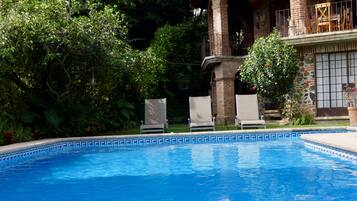 A swimming pool with a brick house in the background.