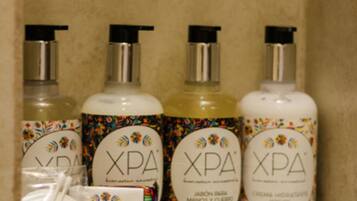 A shelf with three bottles of XPA hand and body care products, a white cloth, and a box.