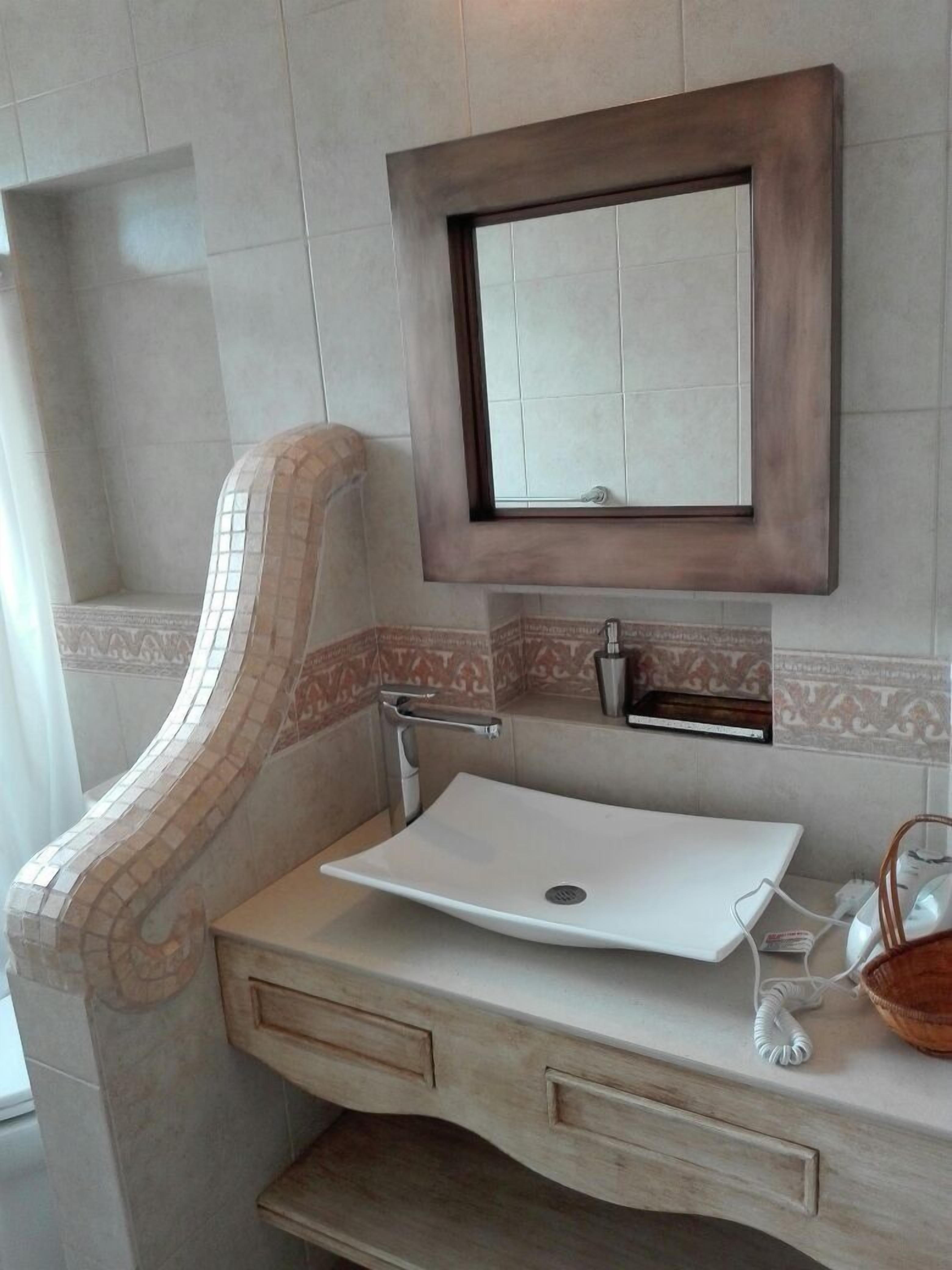 A bathroom with a white sink, a mirror, and a towel rack.