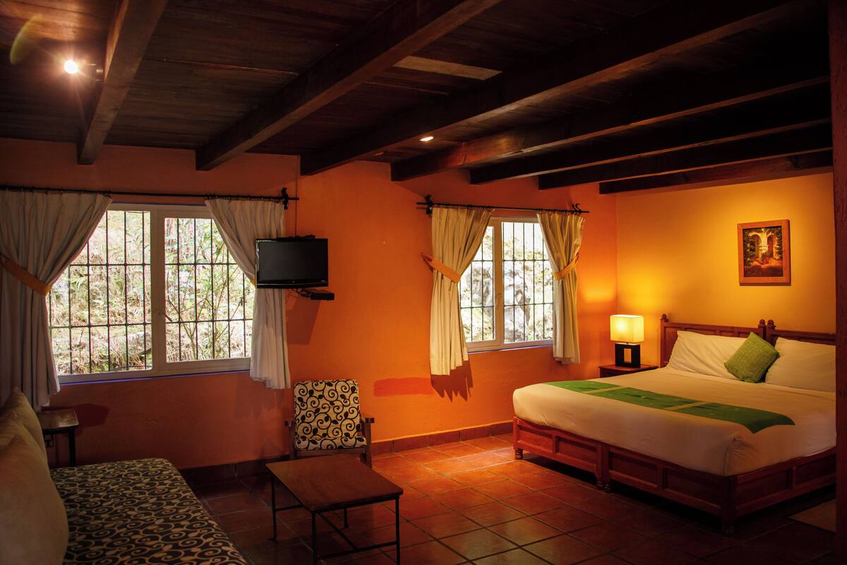 A room with a bed, a chair, a table, and a TV.