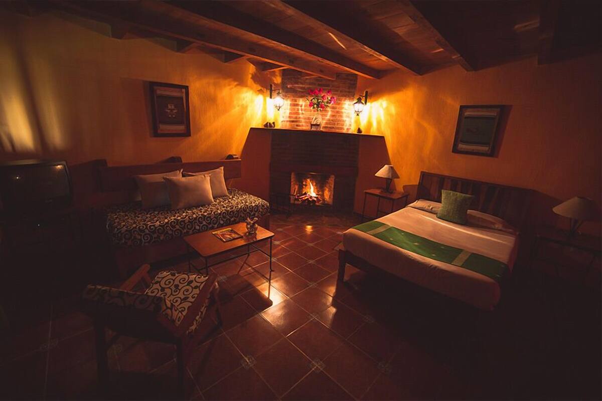 A cozy room with a fireplace, a bed, a sofa, and a small table.