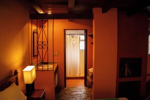 A narrow hallway leading to a bathroom with a stone floor, a sink, and a mirror.