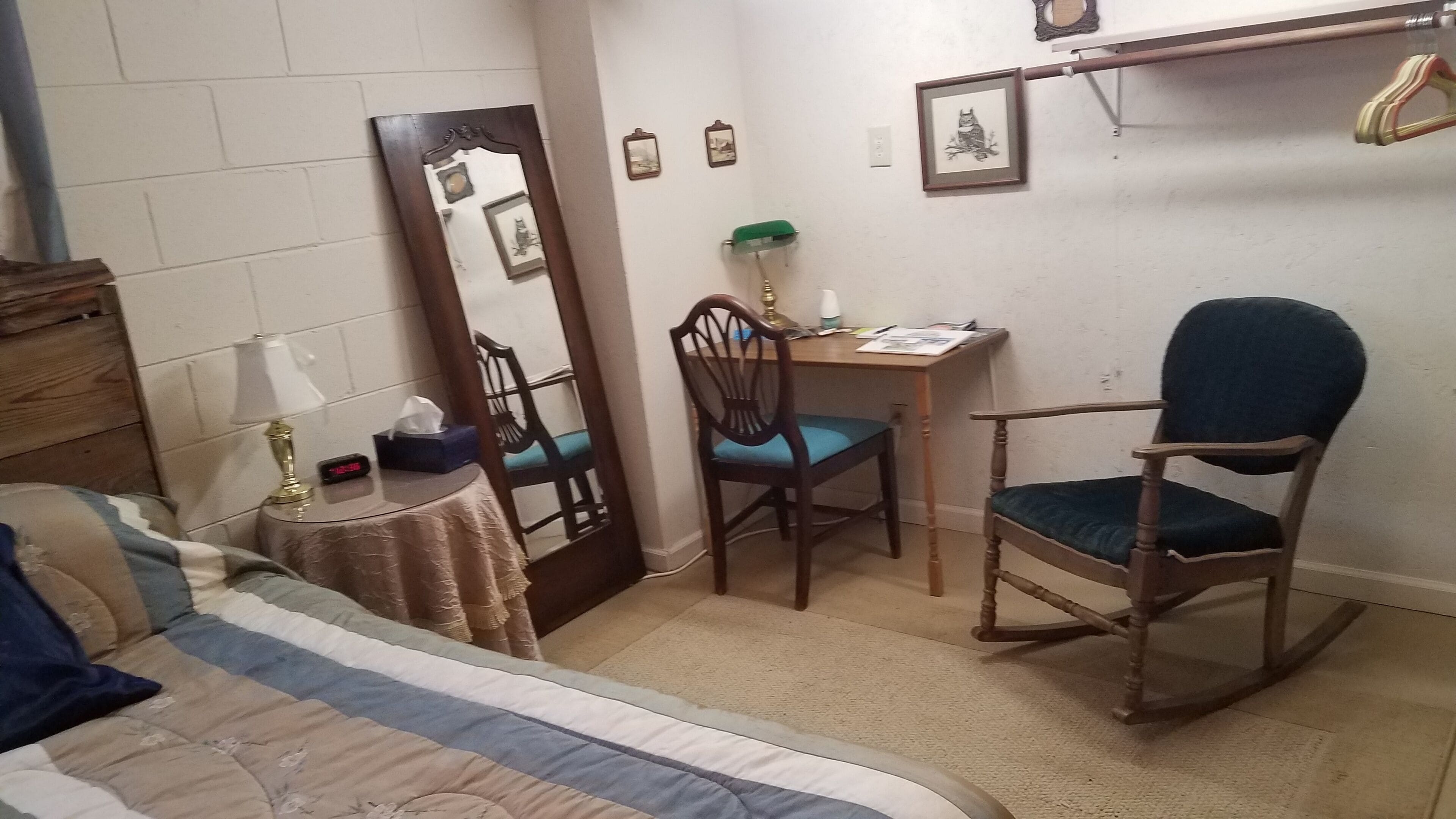 Un dormitorio con cama, escritorio, silla y espejo.