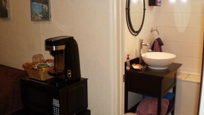 Baño con cafetera, lavamanos y toallero.