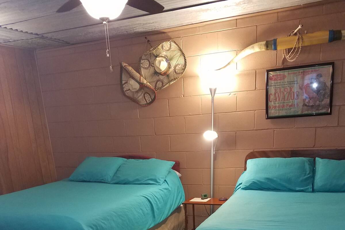 Ein Zimmer mit zwei Betten, einem gemusterten Teppich, einer Wanduhr und einer Pendelleuchte.
