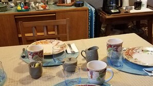 Una mesa de comedor servida con platos, tazas y cubiertos.