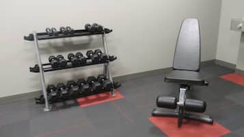 A gym with a bench and a rack of dumbbells.