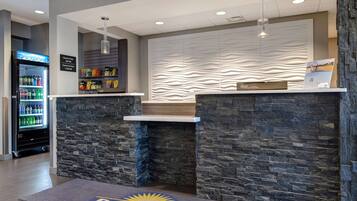 A reception area with a stone wall, a vending machine, and a sign indicating check-in/out times.