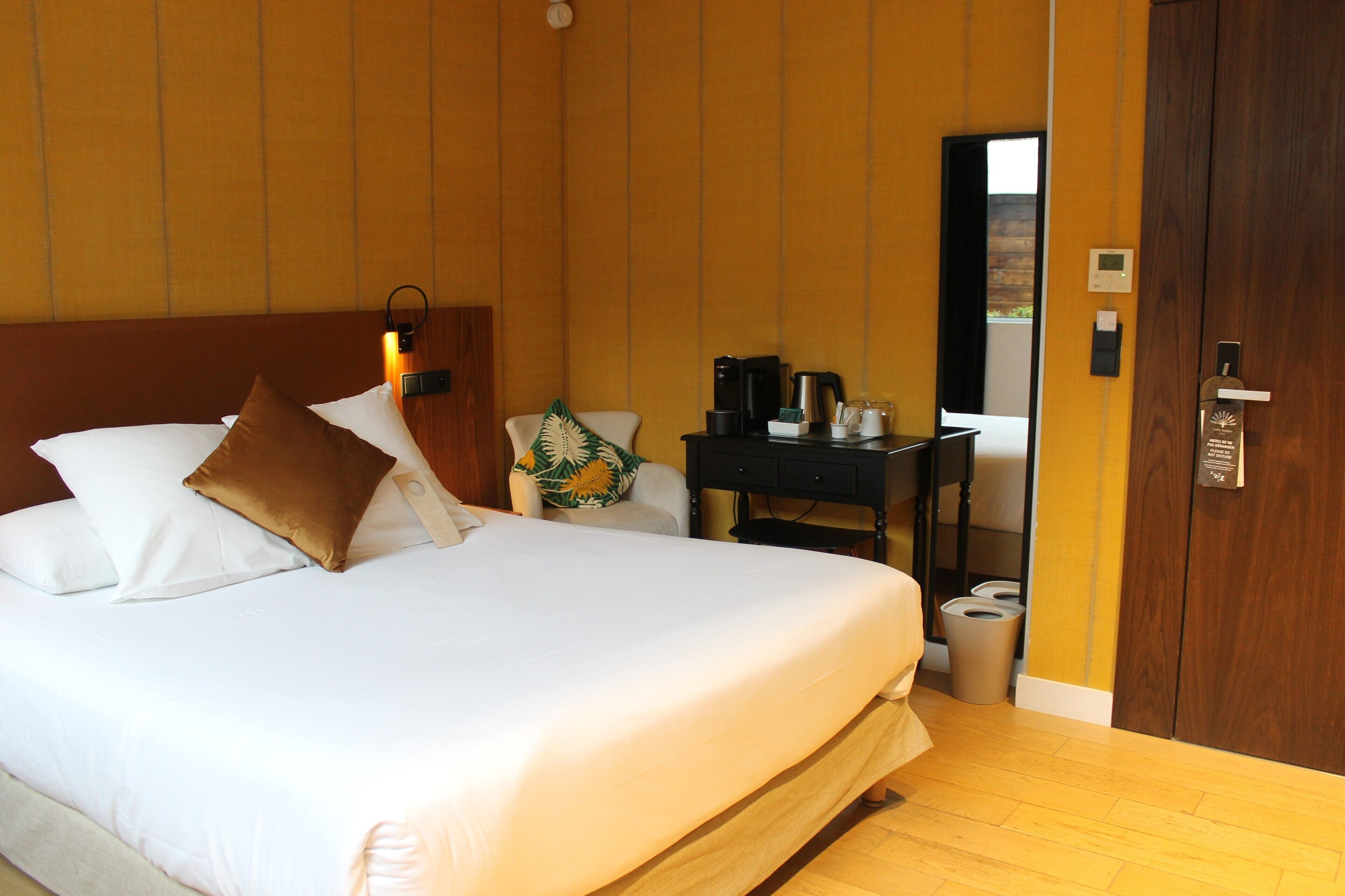 Habitación de hotel con una cama grande, un escritorio con cafetera y un cubo de basura.