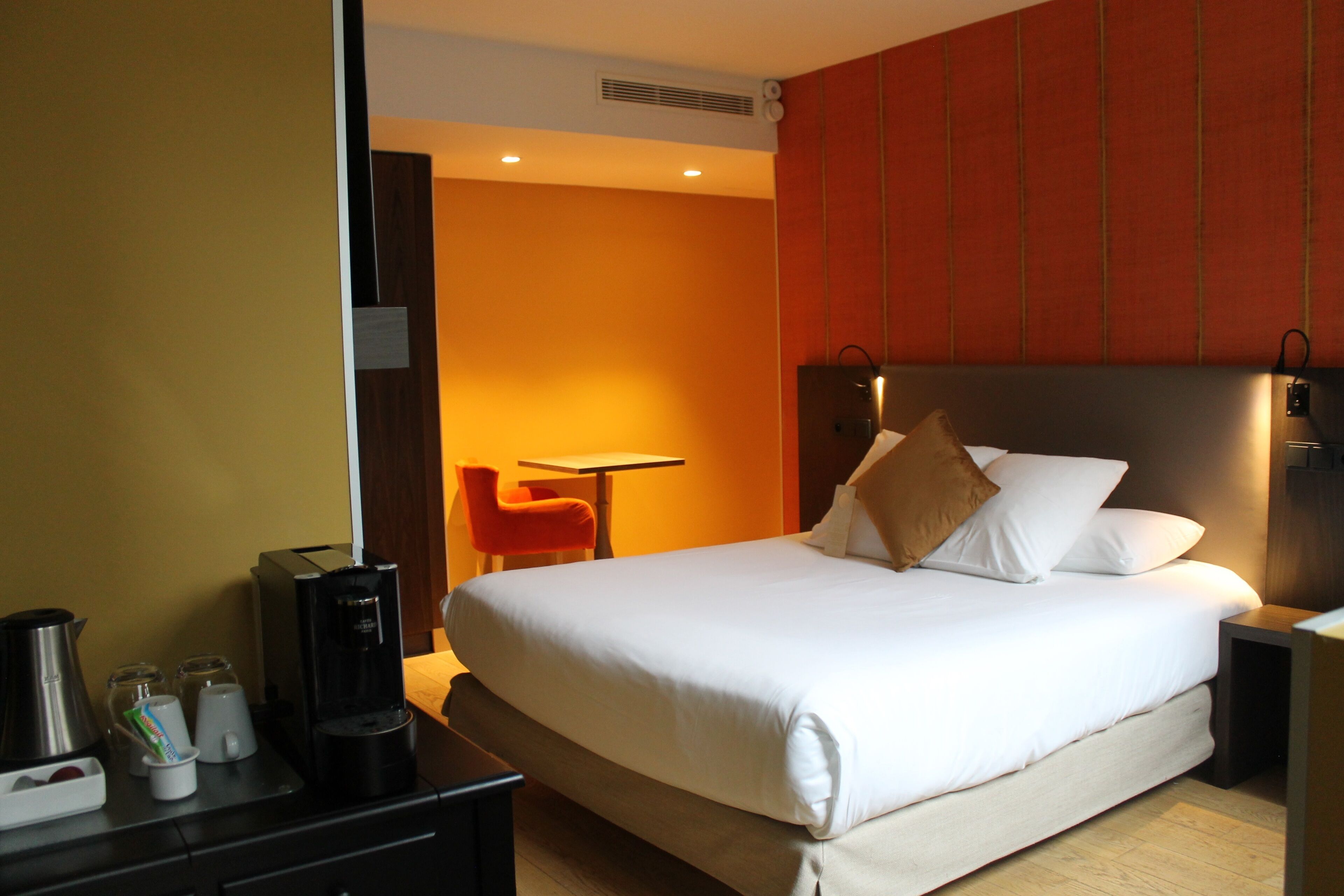 Habitación de hotel con cama, escritorio, silla y cafetera.