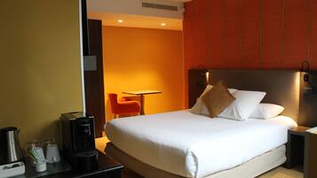 Habitación de hotel con cama, escritorio, silla y cafetera.