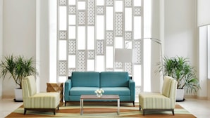 Una sala de estar moderna con un sofá azul turquesa, dos sillones, una mesita de centro y un biombo decorativo.