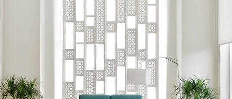 A modern living room with a teal sofa, two armchairs, a coffee table, and a decorative screen.