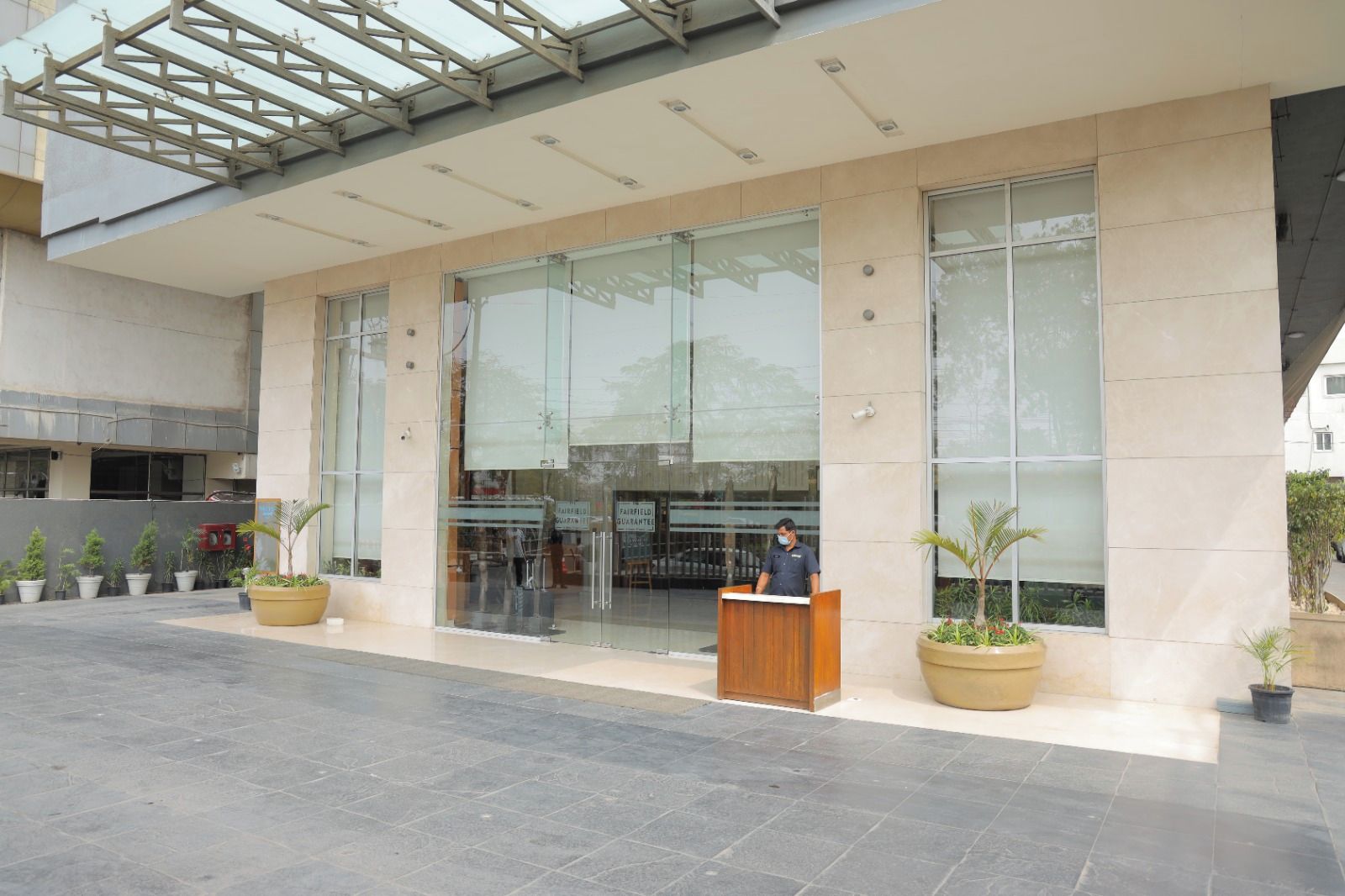 Un edificio moderno con mostrador de recepción, grandes ventanales y plantas en macetas.