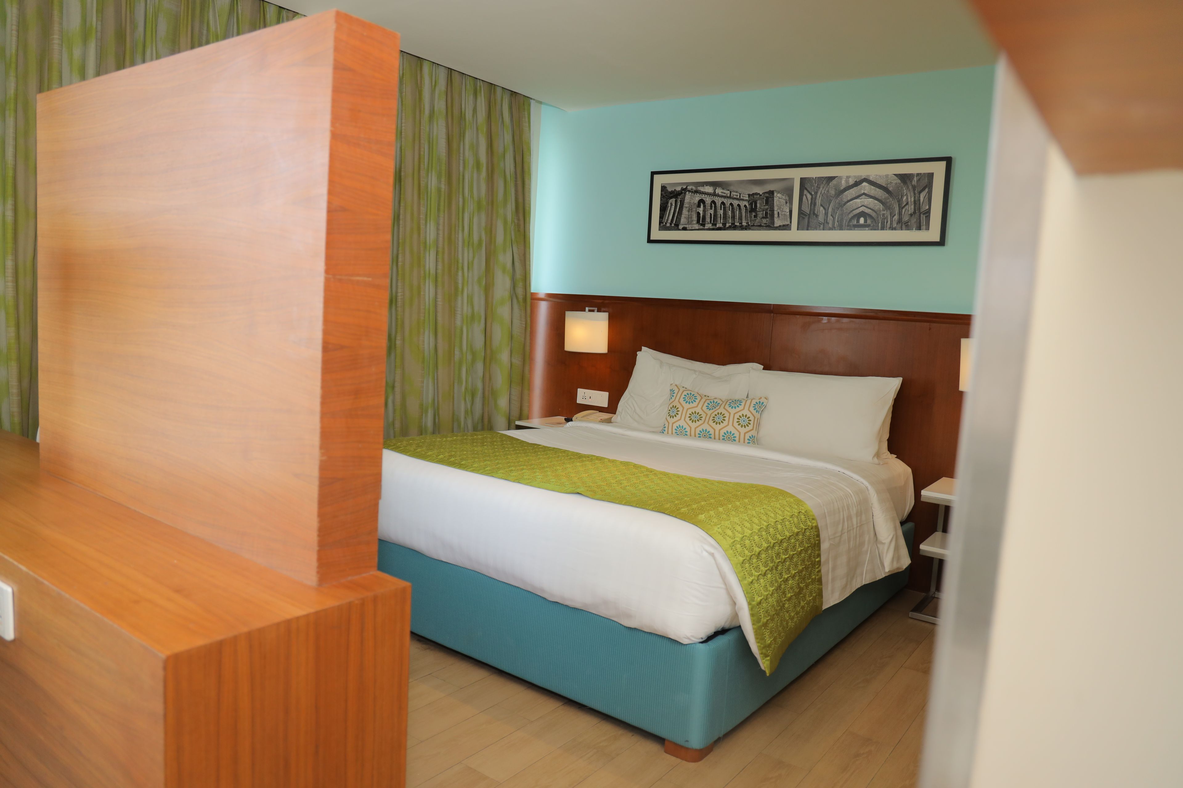 Una habitación de hotel con una cama, una mesita de noche, una lámpara y un cuadro en la pared.