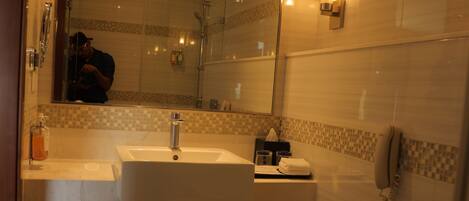Een badkamer met een grote spiegel, twee wastafels, een toilet en een douche.