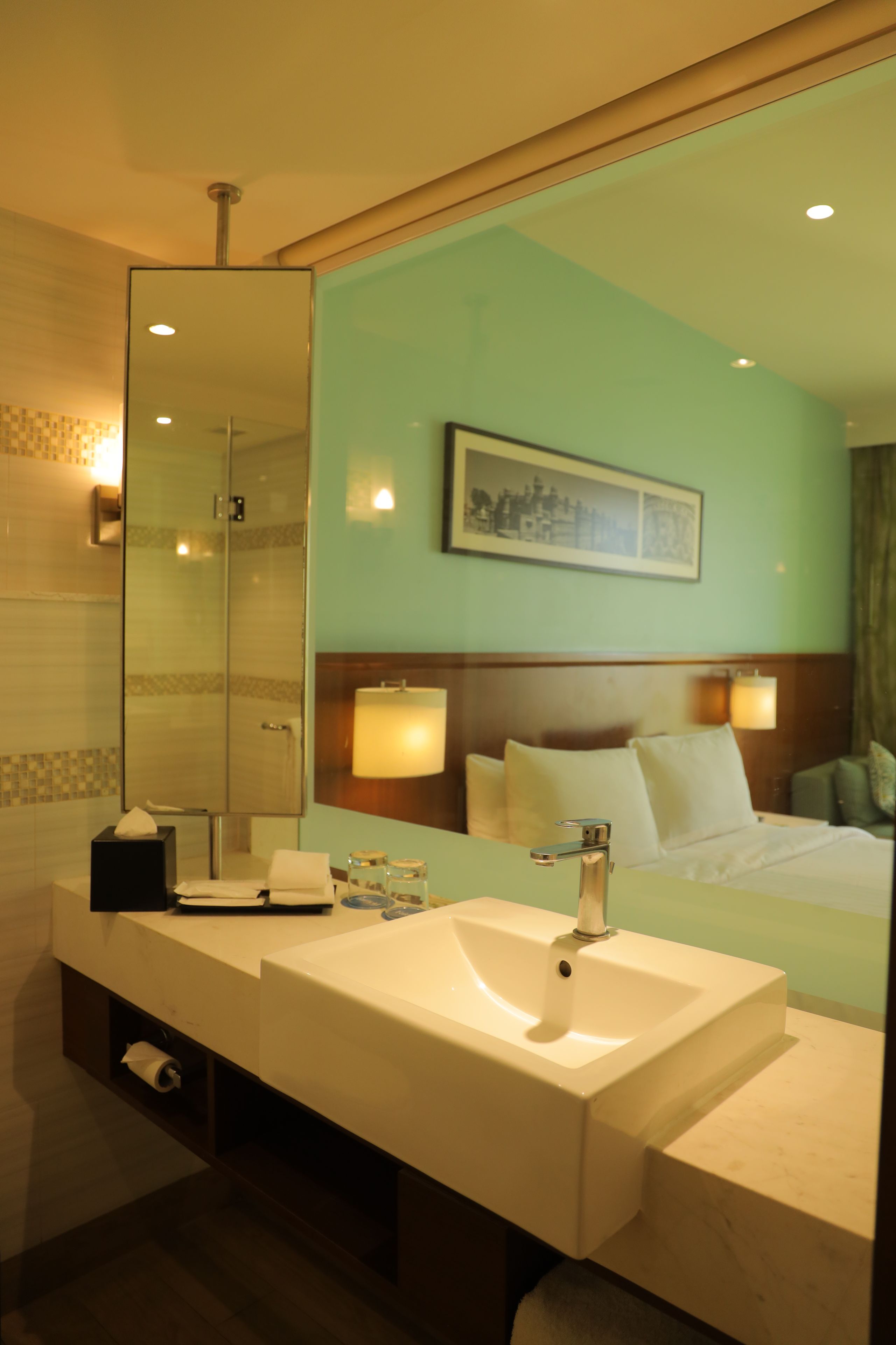 A hotel bathroom with a large mirror, a sink, and a shower.