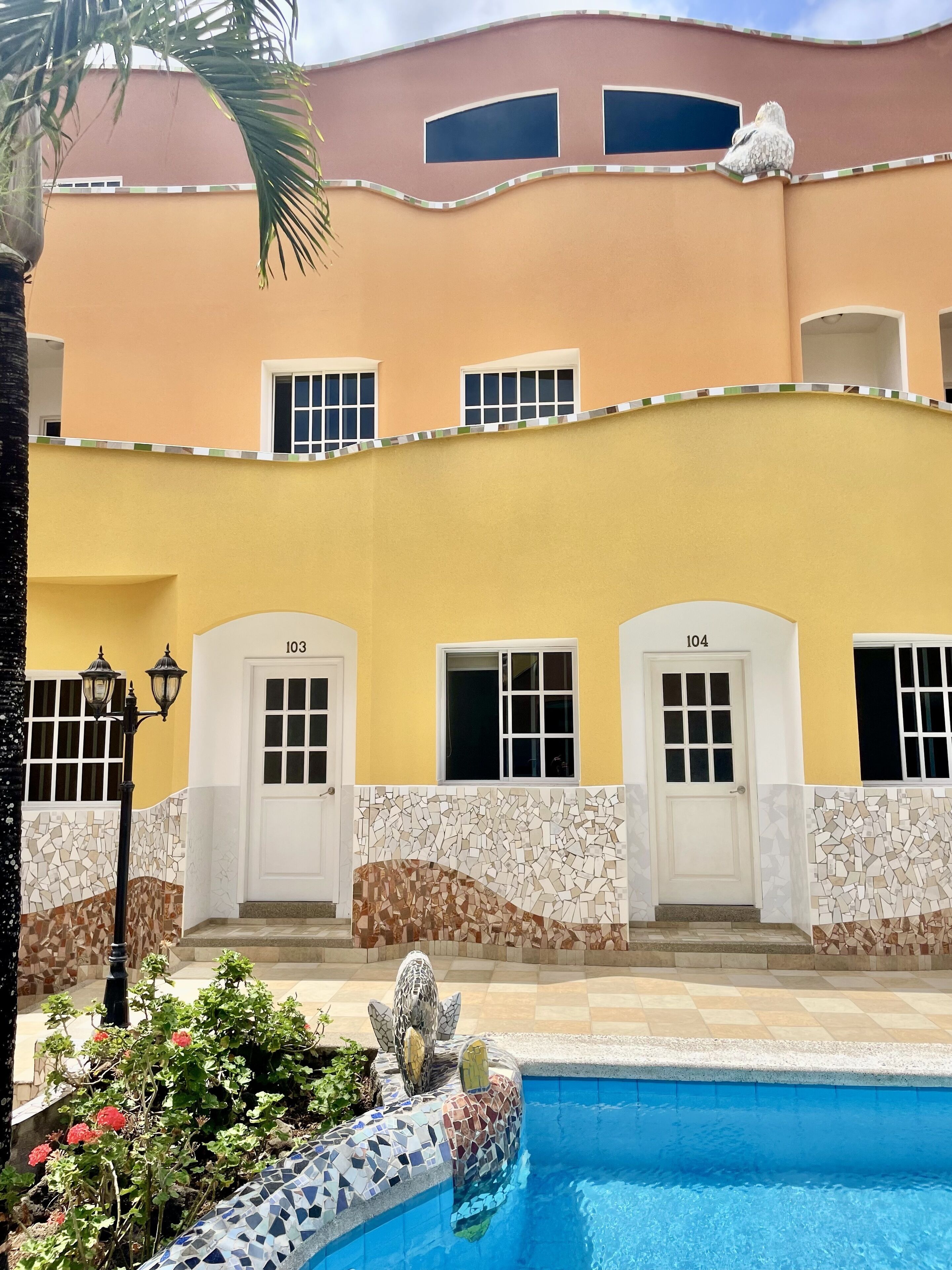A building with numbered doors, a pool, and a mosaic wall.