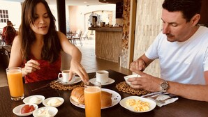 Ein Esstisch mit Frühstücksangeboten, darunter Croissants, Obst und Rührei.