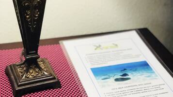 A table with a decorative lamp, a pink textured placemat, and a printed informational card.