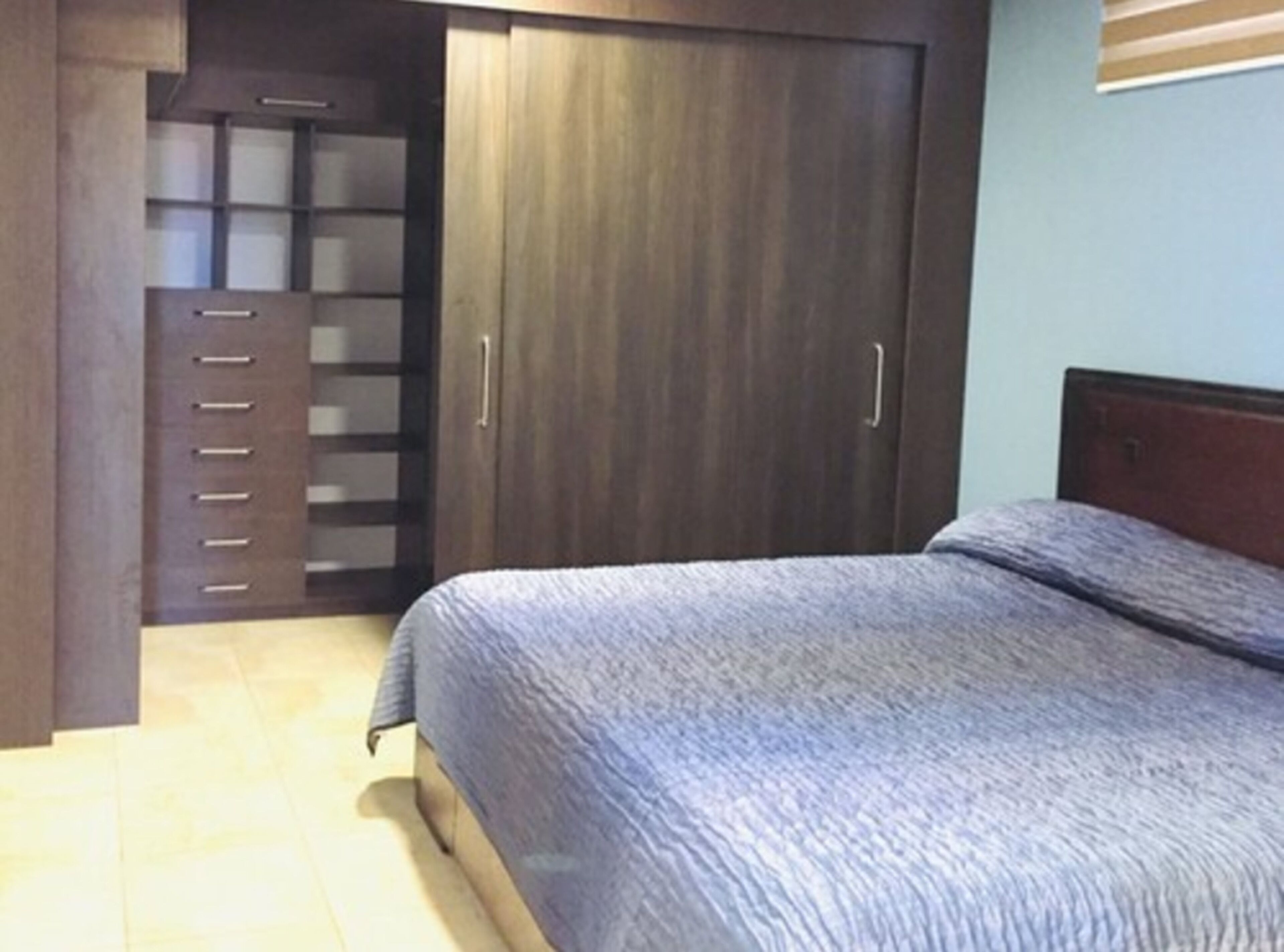 A bedroom with a bed, a wardrobe, and a small cabinet.