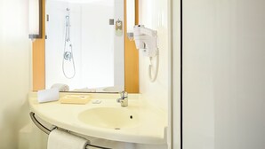 Un baño con lavamanos, espejo, toalla y secador de pelo.