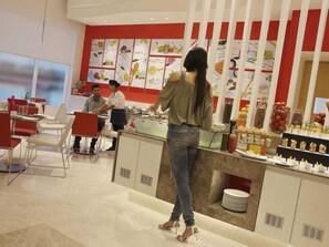 A modern restaurant with red and white decor, a buffet counter, and seating arrangements.