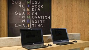 A workspace with two laptops on a wooden desk, a blackboard with words related to social media and internet work behind them. - Ibis Osasco (Osasco)