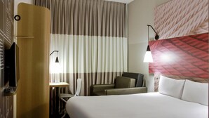 A hotel room with a bed, a desk, a chair, and a TV. - Ibis Osasco (Osasco)