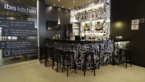 A modern kitchen bar area with a black and white mural, bar stools, and a chalkboard menu. - Ibis Osasco (Osasco)