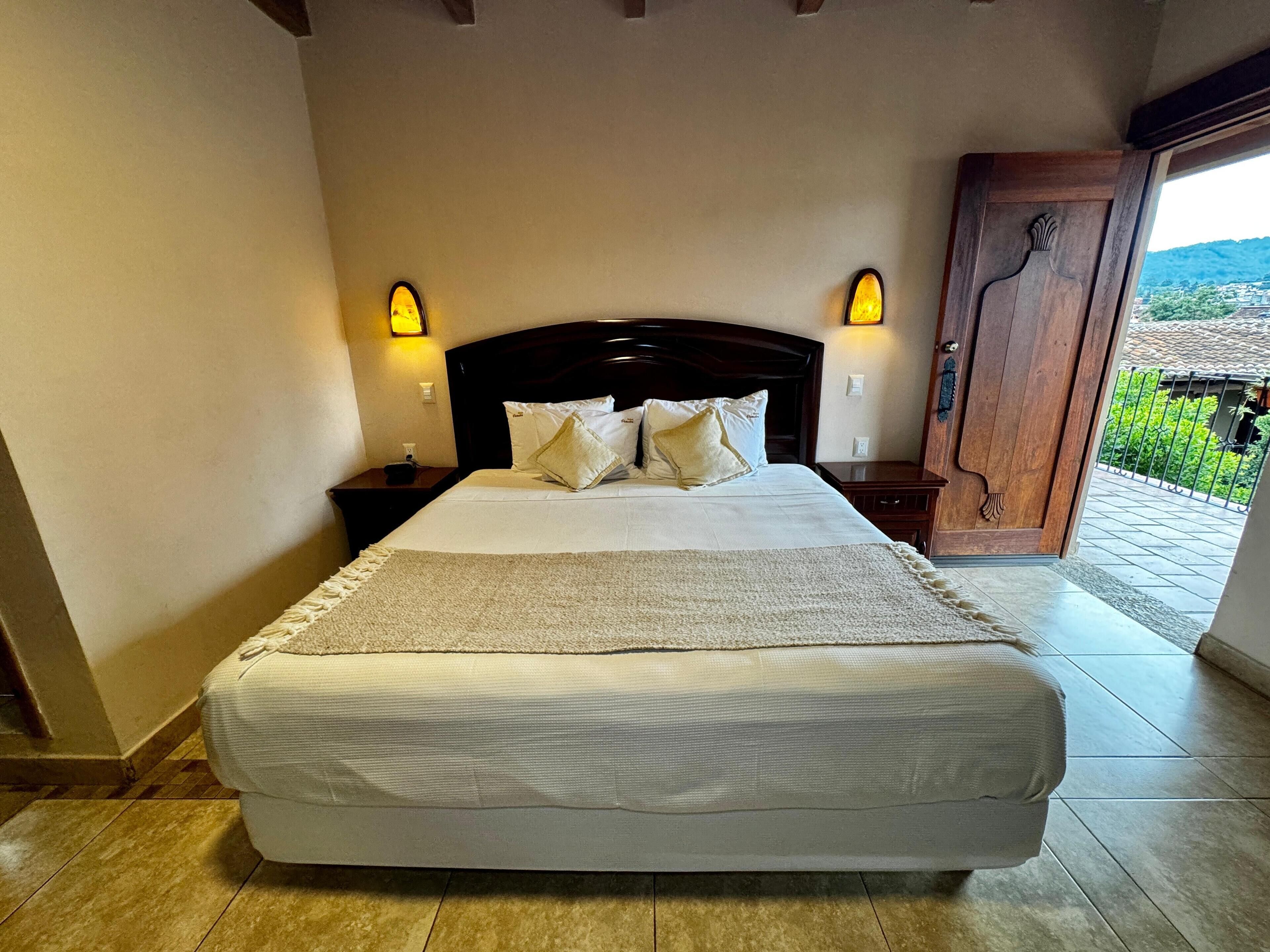 A neatly made bed with a headboard, two bedside tables, and wall-mounted lights.