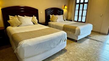 Two single beds with wooden headboards, a nightstand, a bedside table, and a window with curtains.