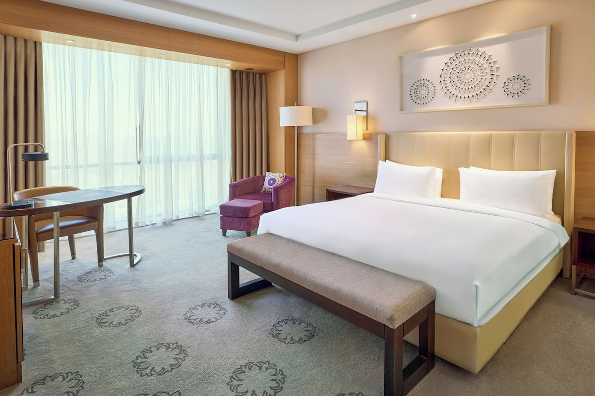Una habitación de hotel con una cama grande, un escritorio, una silla y un banco.