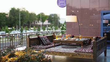A traditional sofa set with cushions and a table, a lamp, and a sign indicating a restaurant.