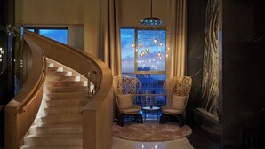 Un magnifique escalier menant à un balcon d’où l’on peut admirer la vue sur la ville au crépuscule.