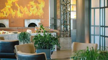A modern interior with a fireplace, seating area, and large windows.
