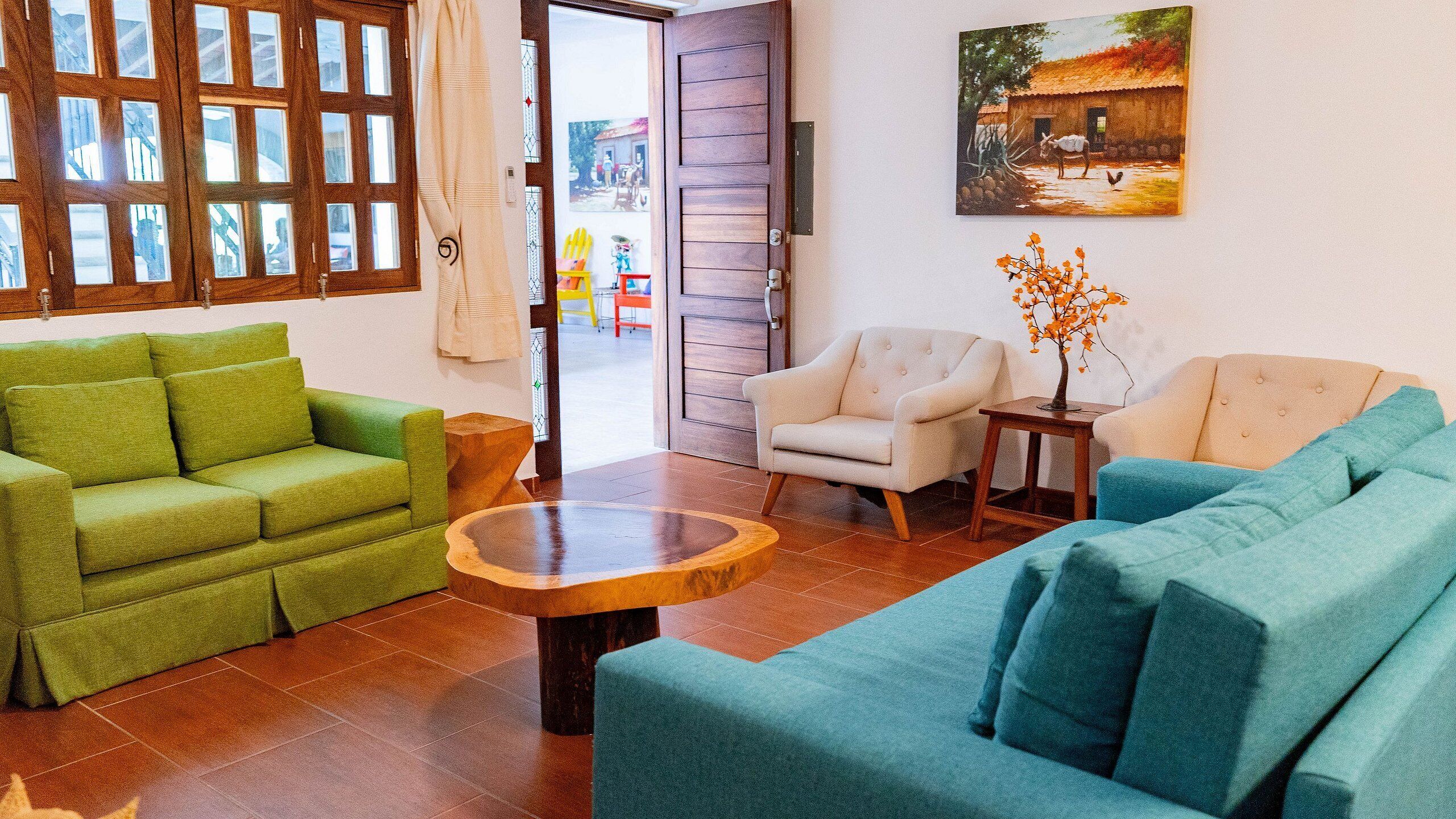 A living room with a green sofa, a blue sofa, a white armchair, and a wooden coffee table.