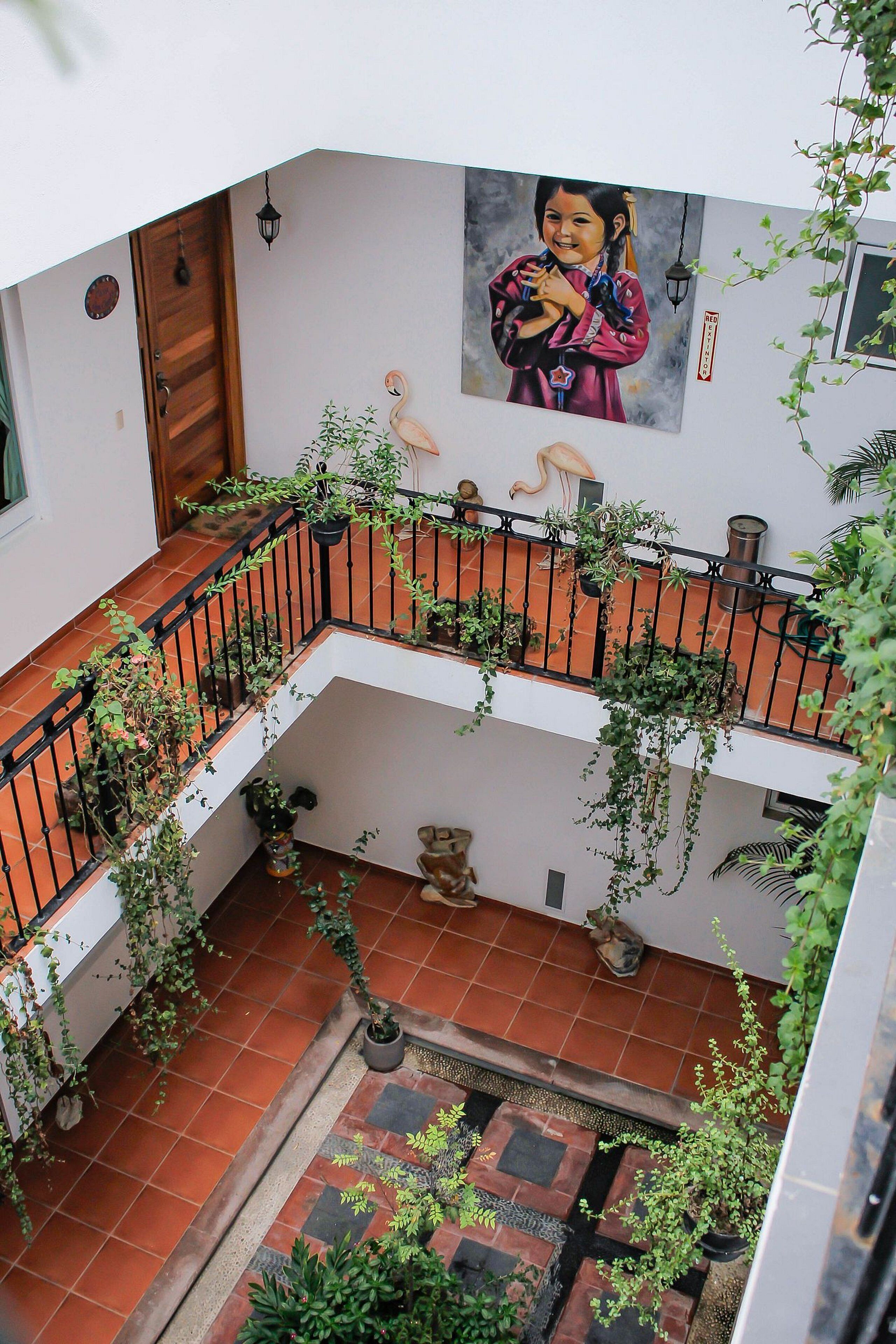 Un intérieur à plusieurs niveaux, avec des planchers carrelés, une porte en bois et un balcon agrémenté de plantes en pot.
