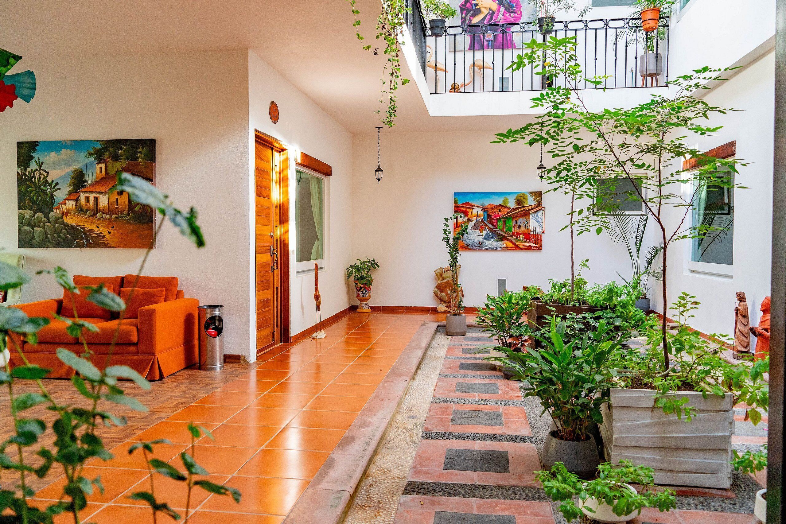 A spacious living area with a sofa, potted plants, and artwork on the walls.