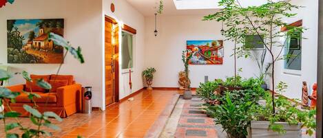 A spacious living area with a sofa, potted plants, and artwork on the walls.